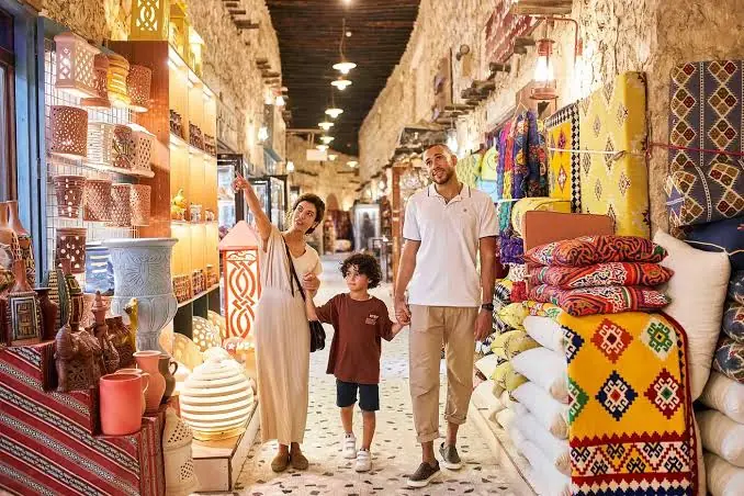 Family walking through the lantern-lit alley of Souq Waqif market in Doha on a full-day Doha highlights tour