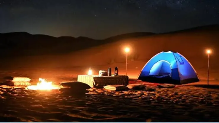Bedouin-style tent with a glowing campfire at night on an overnight desert camp near Doha