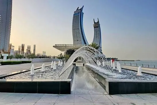 Curved waterfront towers behind arched fountains in Qatar